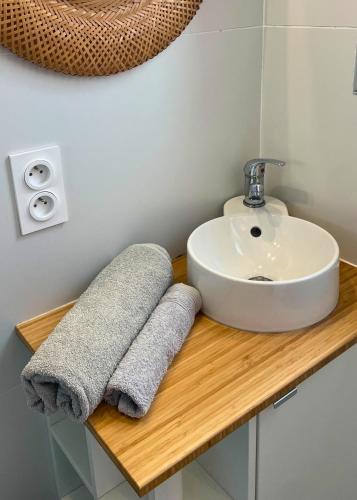 La salle de bains est pourvue d'un lavabo et de serviettes sur un comptoir en bois. dans l'établissement L'authentique - Centre - Calme - Équipé - Basque, à Bayonne