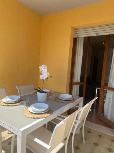 a white dining room table with white plates and chairs at Casa Adele - appartamento vista mare in Villa Rosa