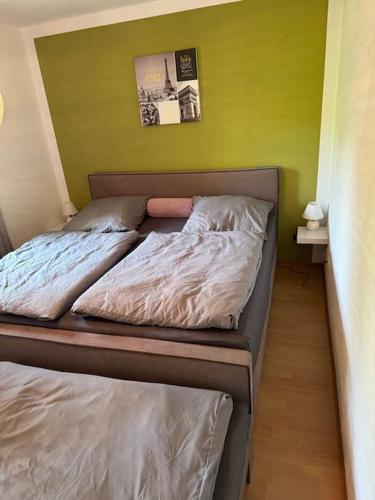 a bed in a bedroom with a green wall at Ferienwohnung 7 Schlafplätze E Ladestation 11 KW in Kirchdorf am Inn