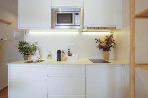 a kitchen with white cabinets and a microwave at Lemon Beach Boutique Studio in Platja  d'Aro