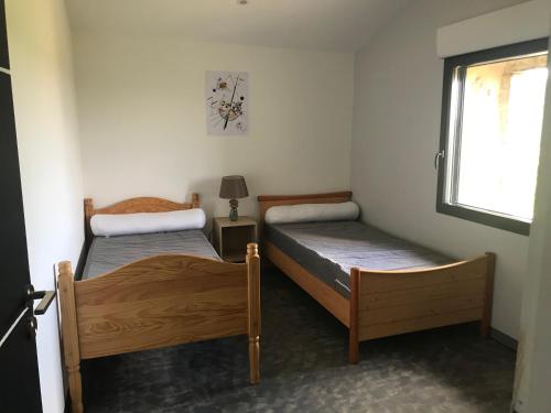 deux lits dans une petite pièce avec une fenêtre dans l'établissement Gîte 10 personnes Ardèche Jacuzzi, à Saint-Apollinaire-de-Rias