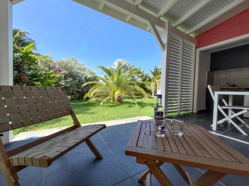 eine Terrasse mit einem Holztisch und einer Bank in der Unterkunft Kaz et Palmiers in Saint-François