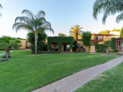 a house with a green yard and palm trees at Sunriver Kalahari Lodge Riverside stay in Upington in Upington