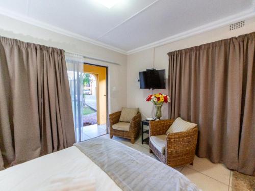a bedroom with a bed and a chair and a tv at Sunriver Kalahari Lodge Riverside stay in Upington in Upington