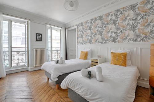 - 2 lits dans une chambre avec des oreillers blancs et orange dans l'établissement Le Petit Hôtel - Appt 6p 127 m² à Paris, à Paris