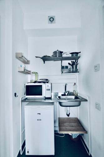 Una pequeña cocina con microondas y fregadero. en Assuta studio, en Tel Aviv
