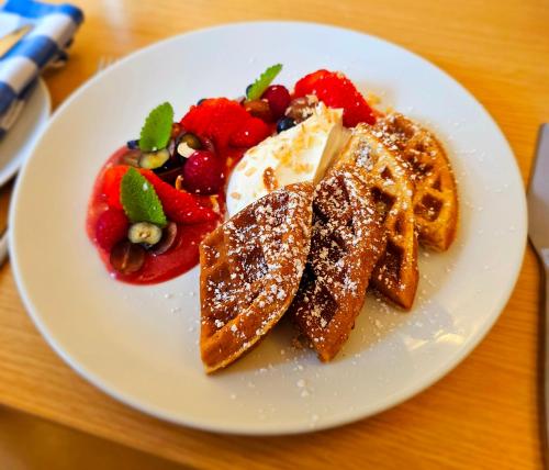 a white plate with waffles and fruit on a table at Eagle View Guest House in Newtonmore