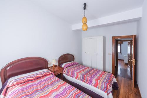 two beds sitting next to each other in a room at Luminoso apartamento reformado en villa termal in Cuntis