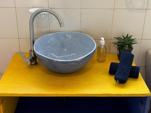 a blue bowl on a yellow counter with a sink at The Seed Pod Guesthouse in Modimolle