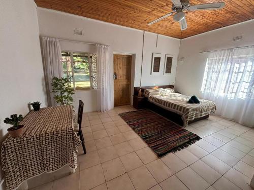 a living room with two beds and a ceiling fan at The Seed Pod Guesthouse in Modimolle