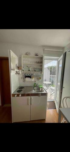 a kitchen with a sink and a stove and a window at Apartments Ćošković in Podgora