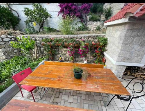 a wooden table with two chairs and flowers on a patio at Apartments Ćošković in Podgora