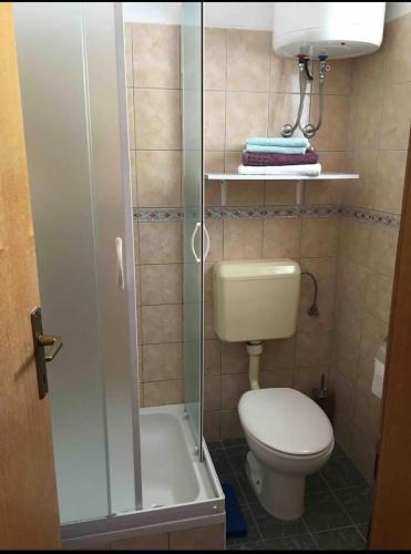 a small bathroom with a toilet and a shower at Apartments Ćošković in Podgora