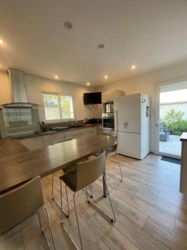 une cuisine avec une table en bois et un réfrigérateur dans l'établissement Maison lumineuse à Porto-Vecchio, à Porto-Vecchio