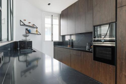 une cuisine avec des comptoirs noirs et des armoires en bois dans l'établissement Elegant apartment - 2BR-4P - Arc de Triomphe, à Paris