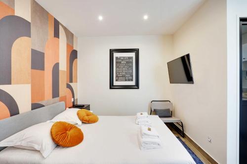 - une chambre avec un lit doté d'oreillers orange et une télévision dans l'établissement Magnificent studio - 2P - Levallois-Perret, à Levallois-Perret