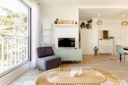 - un salon avec une télévision, une chaise et une table dans l'établissement Studio 119, à Levallois-Perret