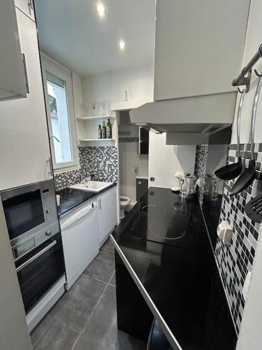 une cuisine avec des armoires blanches et un comptoir noir dans l'établissement Situé à 7 min à pied de Paris Porte de Versailles et Métro, à Issy-les-Moulineaux