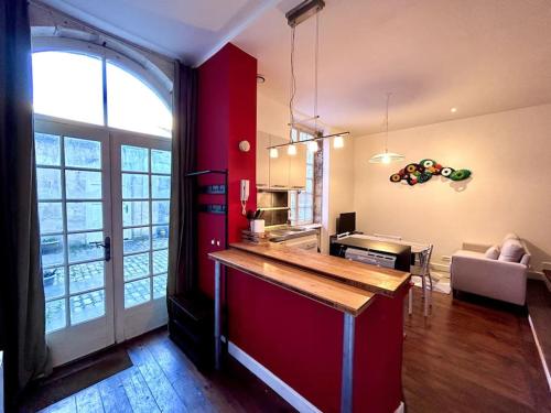 Il comprend une cuisine et un salon avec un mur rouge. dans l'établissement Le Puyravault - Studio situé en plein centre-ville & proche des thermes, à Rochefort