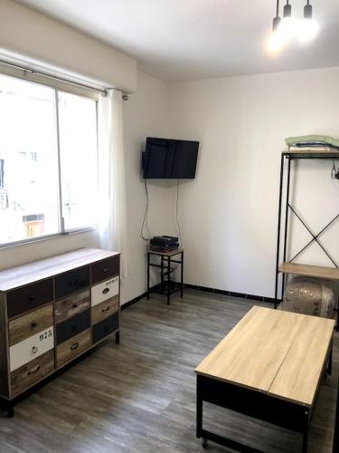 - un salon avec une télévision et une table en bois dans l'établissement studio cosy rénové climatisé, à Alès