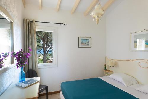a bedroom with a bed and a table and a window at Résidence Marina Di Santa Giulia in Porto-Vecchio