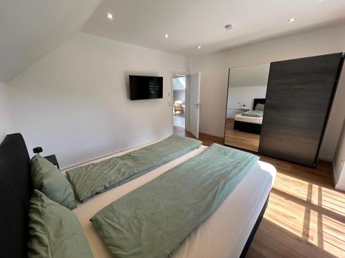 a bedroom with a bed and a tv on the wall at Wellness-Ferienhaus mit Dampfbad & Sauna am Nürburgring in Leimbach