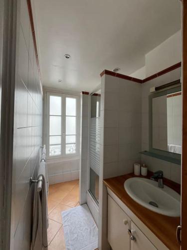 une salle de bain blanche avec un lavabo et un miroir dans l'établissement Magnifique 2p avec vue sur le sacré coeur, à Paris