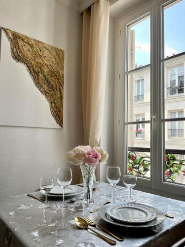 une table avec des assiettes, des verres et un vase de fleurs dans l'établissement Magnifique 2p avec vue sur le sacré coeur, à Paris