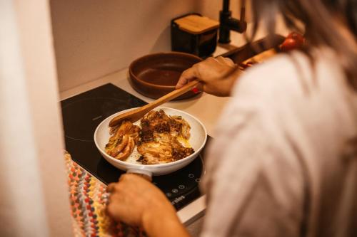 a person cooking food in a bowl on the stove at Vinha by NHôme in Ponte de Lima
