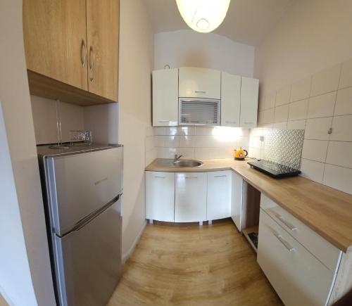 kuchnia z białymi szafkami, zlewem i lodówką w obiekcie Apartamenty Kolorowe Etna w Kołobrzegu