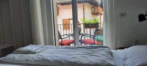 a bedroom with a bed and a balcony with chairs at Orizzonti d'Anaunia in Tassullo