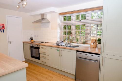 a kitchen with white cabinets and a sink and a window at Herons Lodge in Abergavenny