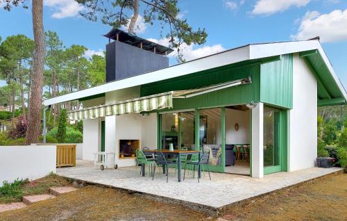 une maison verte et blanche avec une table et des chaises dans l'établissement Nice Home In Lege-Cap-Ferret With Wifi, à Lège-Cap-Ferret