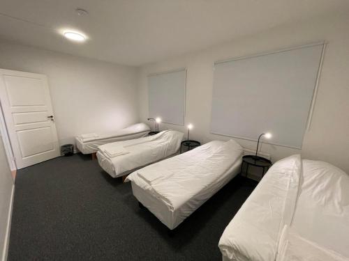 three beds in a room with white walls at Office Motel in Gothenburg