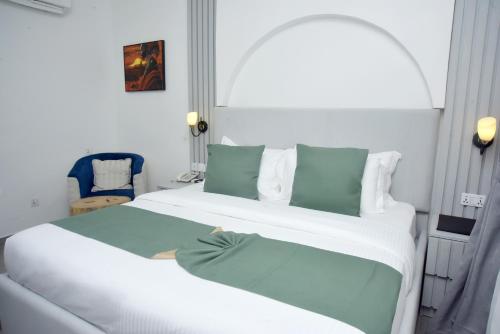 a white bed with green pillows in a room at The Hague Maitama in Abuja