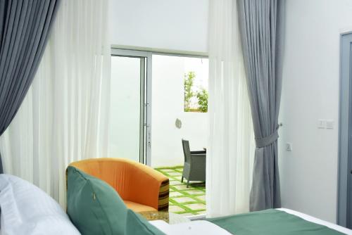 a room with a bed and a chair and a window at The Hague Maitama in Abuja