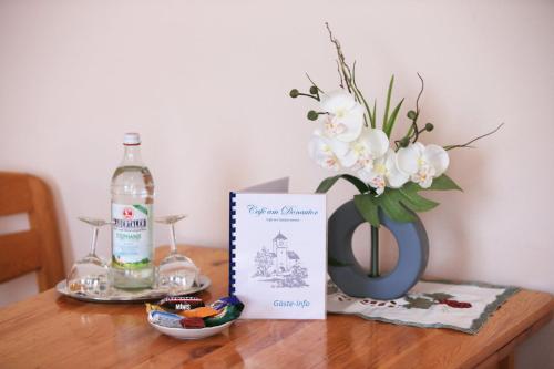 a table with a bottle of wine and a vase of flowers at Café am Donautor in Kelheim