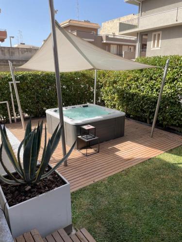 a backyard with a swimming pool and a tan umbrella at Villetta & Suite Angela Pozzallo 150mt mare v Auriga in Pozzallo