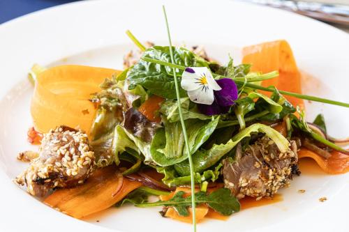 a white plate with a salad with a flower on it at Relais Vosgien - Hôtel Restaurant "la Table de Sophia" in Saint-Pierremont