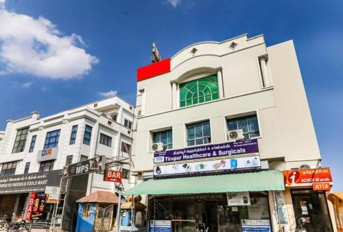 a tall white building with a sign on it at Hotel MPS in Tiruppūr