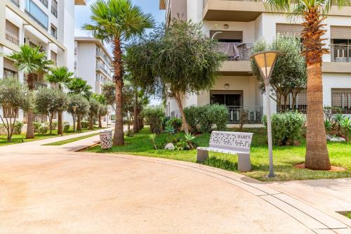 a park with a bench and palm trees in front of a building at AeroSerenity in Nouaceur