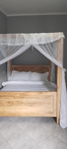 a wooden bed with a canopy in a bedroom at Meuly Family Lodge in Arusha