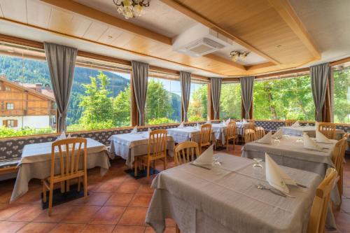 a restaurant with tables and chairs and large windows at Albergo alla Posta in Madonna di Campiglio