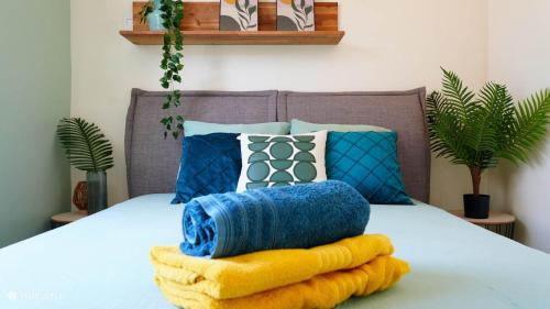 a bed with blue and yellow blankets and pillows at 4BlessingsCuracao2 in Willemstad
