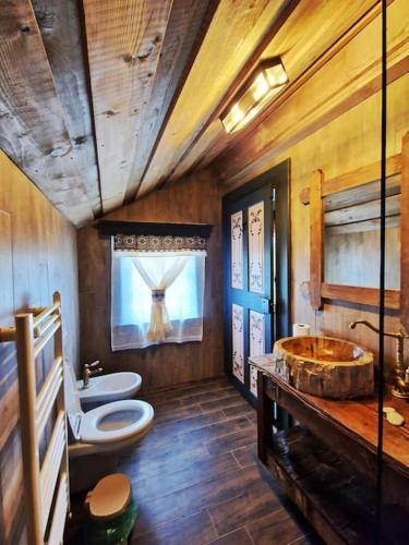 a bathroom with a tub and a toilet and a sink at Căsuță tradițională cu ciubăr și saună în Bran - Casa de la Nuci in Sohodol