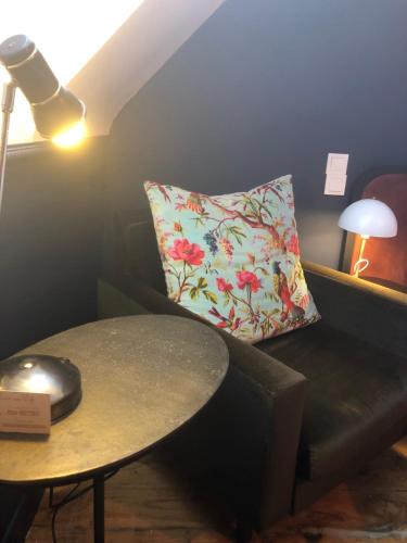 a room with a table and a couch with a pillow at La Maison aux murs anciens et ses chambres in Tarbes