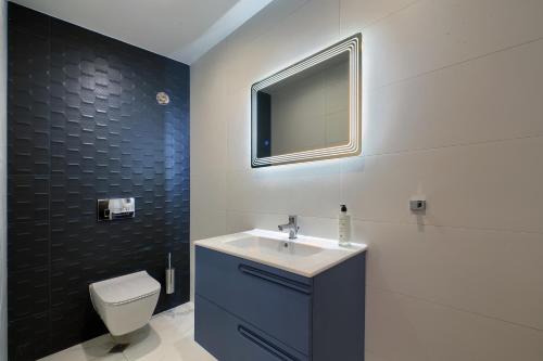 a bathroom with a sink and a toilet and a tv at Aurora Sofia in Sofia