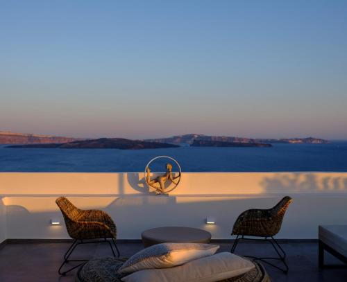 a room with chairs and a table with a view of the ocean at Oia Treasures Art Suites in Oia