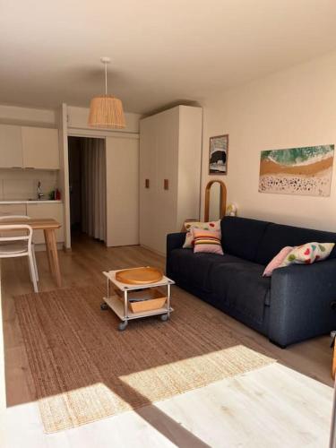 un salon avec un canapé noir et une table dans l'établissement An Héol-Carnac- Confort- La plage à pieds -Jardin plein sud, à Carnac