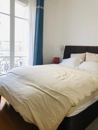 une chambre avec un grand lit blanc avec une fenêtre dans l'établissement Comfortable and Luxury Appart-Center of Paris, à Paris